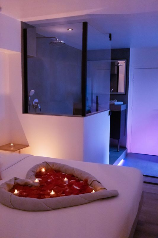 Cœur en serviettes et pétales de rose sur le lit de la suite